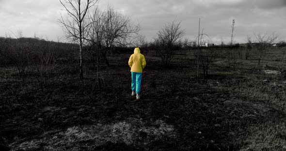 Teenage Homeless Girl in Colorful Ukrainian Clothes Walks on a Burnt Field