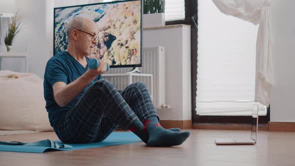 Senior Man Exercising with Dumbbells on Yoga Mat