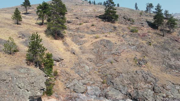 A steep, rocky cliff falling into Okanagan lake with one lonely boat anchoring near the shore. Backw