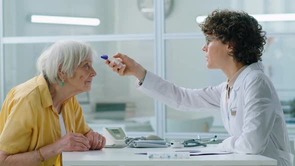 Doctor Measuring Temperature of Elderly Woman