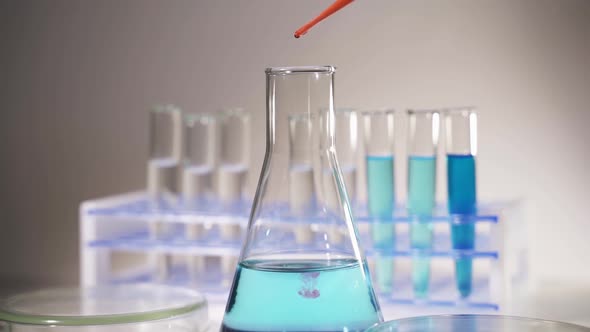 In a Futuristic Laboratory a Scientist with a Pipette Analyzes a Colored Liquid To Extract the DNA