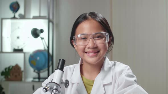 Close Up Young Scientist Girl Looking At Microscope And Smiles In Laboratory Experiment With Liquid