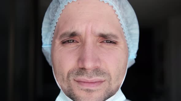 Portrait of a tired doctor who takes off his mask with a sad look and tears in his eyes