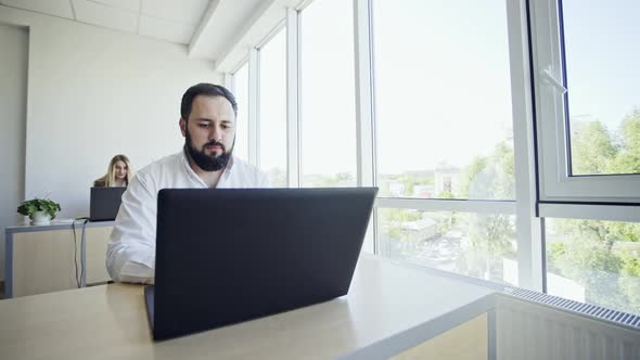 Bearded Businessman Sitting Typing on a Laptop