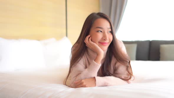 Asian woman relax on bed in bedroom interior