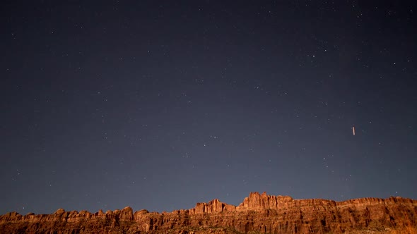 Night timelapse looking over red cliffs lit by full moon