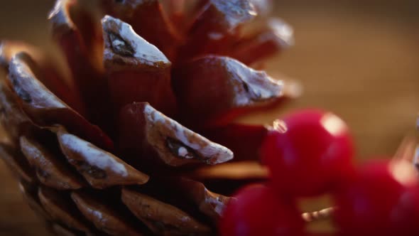 Pine cones with fake snow and cherry on wooden plank