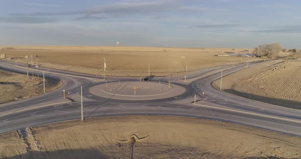 A modern roundabout in the middle of nowhere,  Cars navigate a circle.