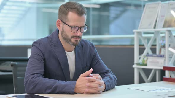 Middle Aged Businessman Thinking While Sitting in Office