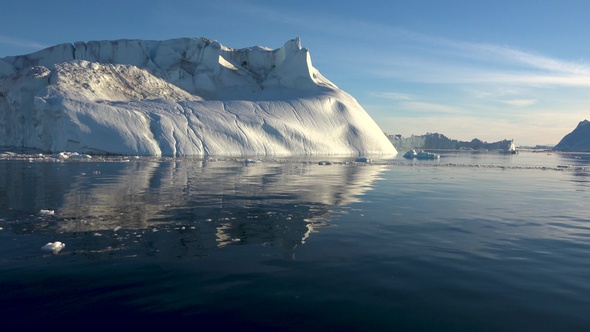 Antarctica. Cruise trip. Sailing along a huge glacier, which is illuminated by the sunset rays.