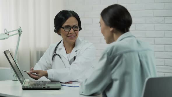 Doctor showing test results on laptop, effective treatment, patient recovering