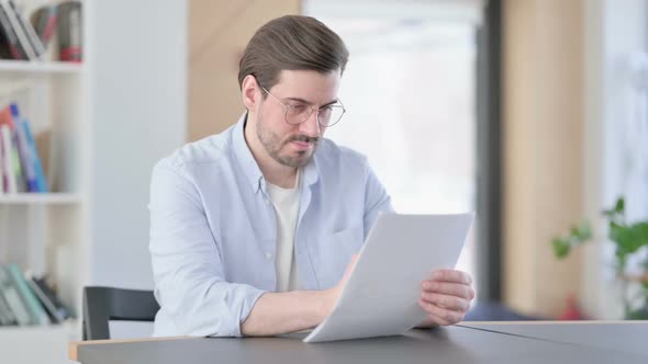 Man in Glasses Reading Documents in Office