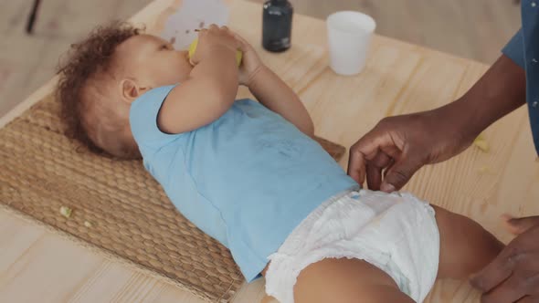 Male Hands Putting New Nappy on Child