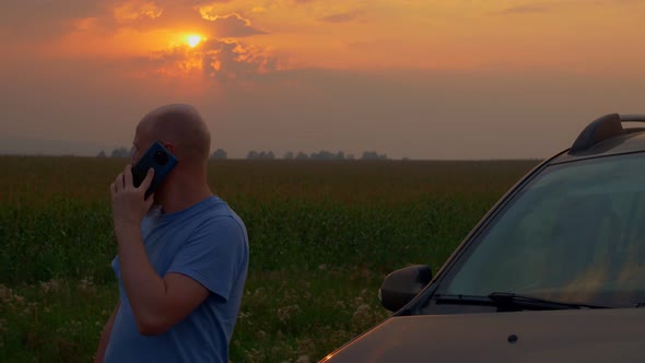 A Bald Bearded Man Stands By His Broken Car on the Side of the Road