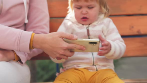 A mother turns on cartoons on her phone and gives it to her little child.
