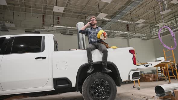 Contractor Worker Talking on His Phone While Seating on Pickup Truck Bed