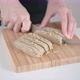 Young woman hands cut brown halva into slices on wooden cutting board with sharp steel knife - VideoHive Item for Sale