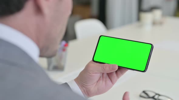 Businessman Looking at Smartphone with Green Chroma Key Screen