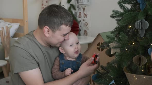 Father Showing Decorated Christmas Tree to Baby