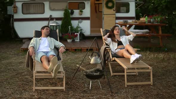 Happy Young Couple Having Rest Close to a Campsite with Hanged Kettle