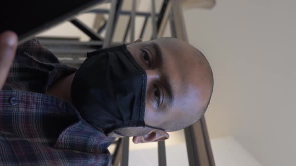 Adult Male Wearing Face Mask Checking Mobile Sitting Down On Stairwell. Vertical Video, Close Up, Lo