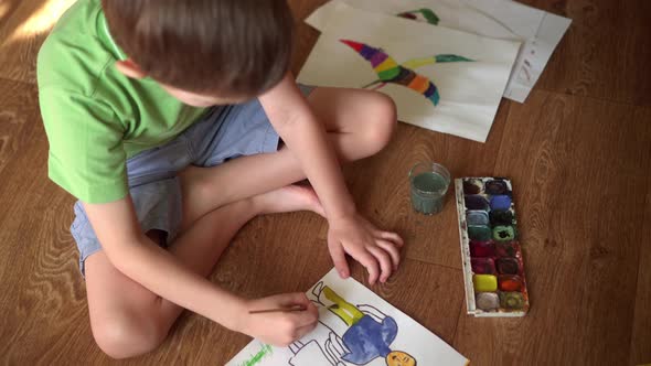 A Child on the Floor Draws a Drawing with Watercolors