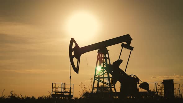 Silhouette of Working Oil Pump From Oil Field at Sunset. The Industrial Equipment.