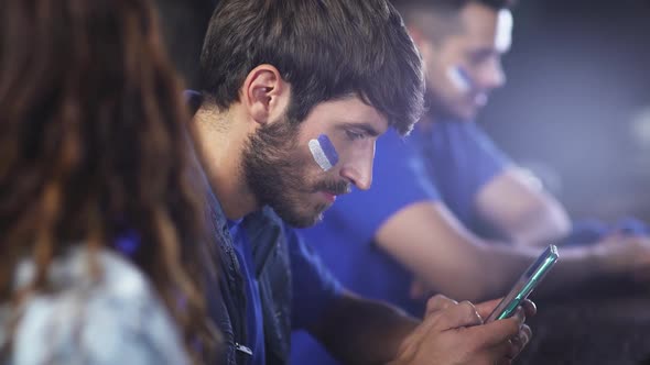 Football Fans are Sitting in a Bar During a Football Match and Using Their Smartphones Man is Typing