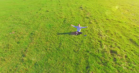 Low Orbital Flight Around Man on Green Grass with Notebook Pad at Yellow Rural Field.