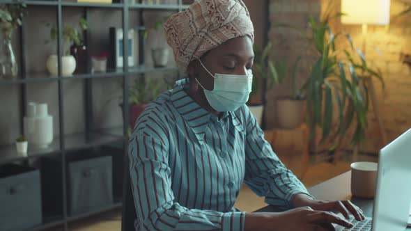 Black Businesswoman in Mask Working on Laptop in Office