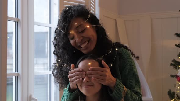 Brunette Girl and Black Mother Hug Wrapped with Garland