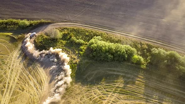 Top down aerial view of fast driving car on dirt road leaving cloud of dust behind.