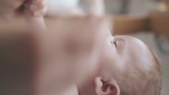 Skilled Nurse Crosses Smiling and Laughing Newborn Boy Arms