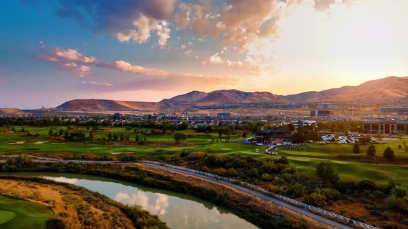 Aerial hyperlapse of an idyllic community with a river and golf course in the foreground and a offic