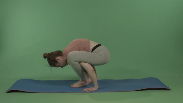 A Young Pretty Girl Does Yoga on a Background of Green Chromakey