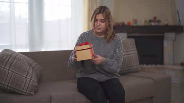 Chubby Woman Find Gift Which Was Left for Her on Sofa. Plump Girl Opening Box with Red Ribbon