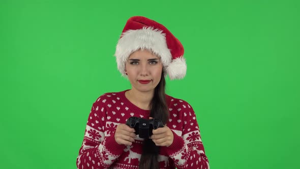 Portrait Girl in Santa Claus Hat Is Playing Video Game Using a Wireless Controller and Rejoicing in