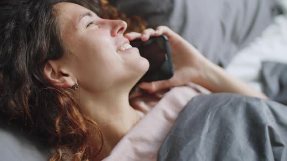 Cheerful Woman Talking on Phone in Bed