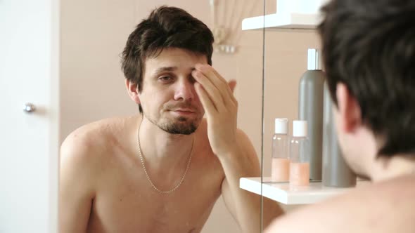 Tired Man Who Has Just Woken Up Looking at His Reflection in the Mirror and Straightens His Hair