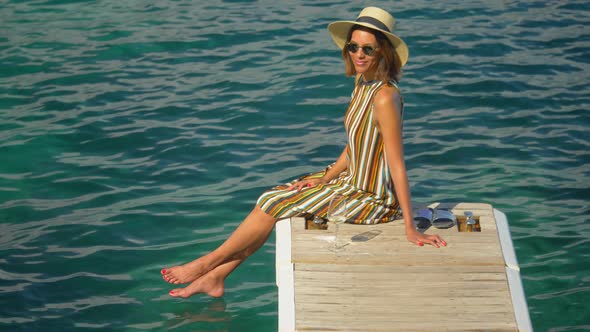 A woman with a glass of white wine on a dock over the Mediterranean Sea in Italy, Europe.