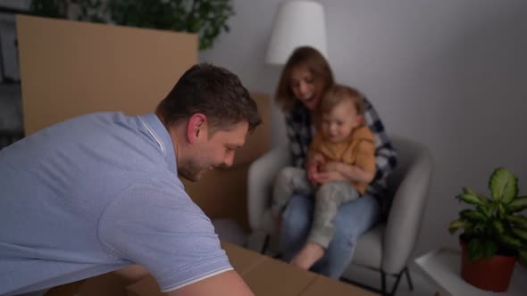 First House Dad Brings in a Cardboard Box Mom and Little Son Help to Unpack