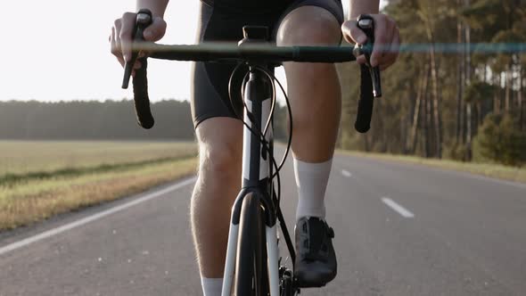 Closeup of Man Riding a Road Bike at the Sunset on a Highway Wearing Helmet