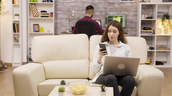 Girl Using Her Phone and Laptop While Sitting on Couch