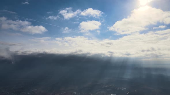 Aerial View From High Altitude of Distant City Covered with Puffy Cumulus Clouds Flying By Before