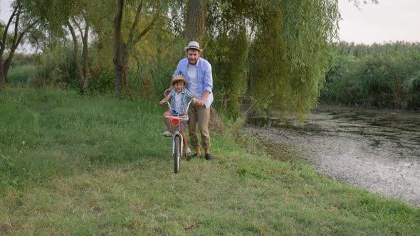 Father and Son Learning To Ride Bicycle Having Fun Together on Background Outdoor Nature and Small