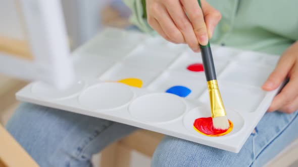 Asian young talented woman artist coloring on painting board with watercolor in house.