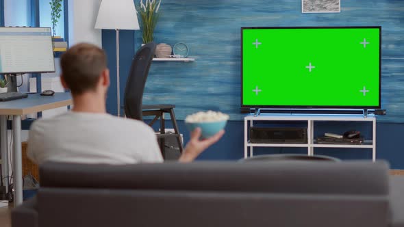 Man Relaxing on Couch Looking at Green Screen on Tv Watching Movie While Eating Popcorn