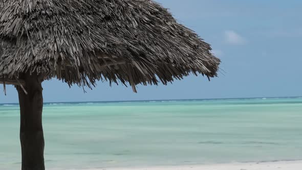 Thatched Umbrella on the Sandy Beach By Ocean Straw Parasol Zanzibar Africa