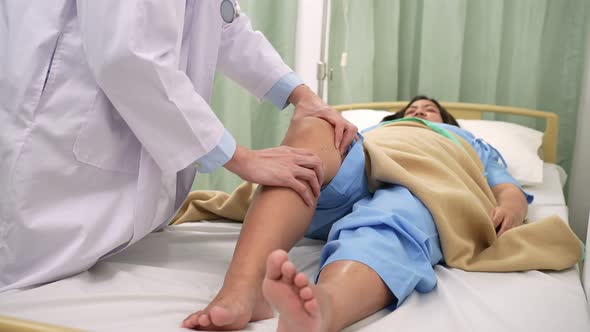 Doctor Physiotherapist examining treating injured knee of pregnant on bed and using handle to the pa