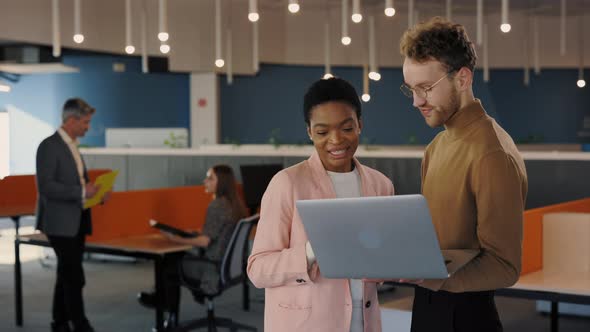 Handsome Office Worker Showing Something to His Female Coworker at the Laptop